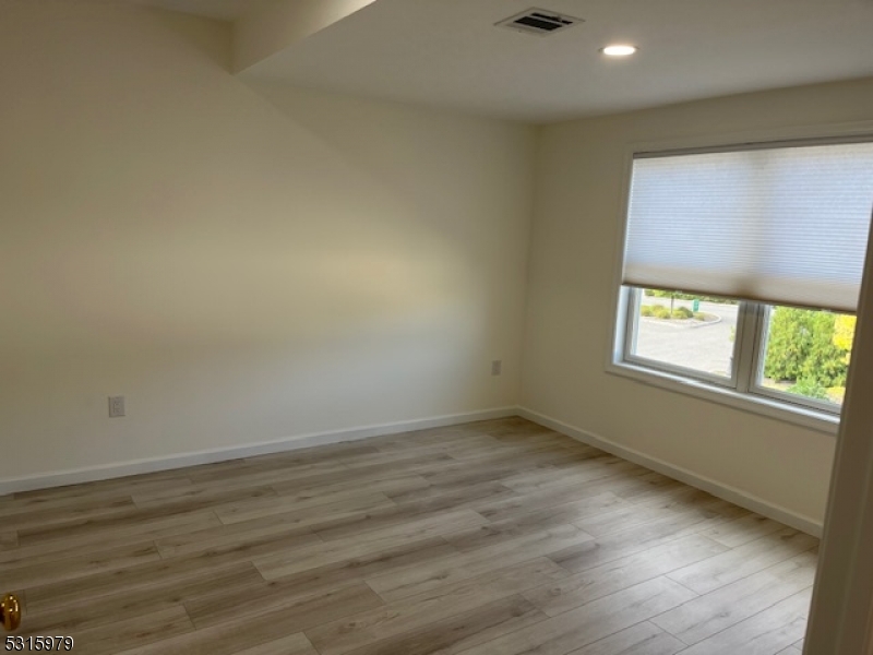 1283 Springfield Avenue, Unit B New Providence, NJ 07974 - Photo 6 of 15 an empty room with wooden floor and windows