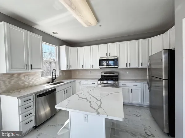 a kitchen with a sink a stove a refrigerator and white cabinets