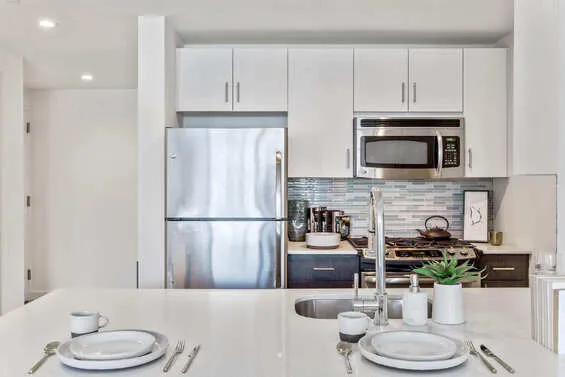 a kitchen with stainless steel appliances a microwave a refrigerator a stove a microwave and dining table