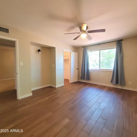 a view of empty room with wooden floor and fan