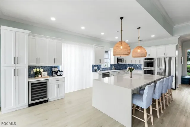 a large kitchen with stainless steel appliances kitchen island granite countertop a stove a sink a refrigerator and a dining table with wooden floor