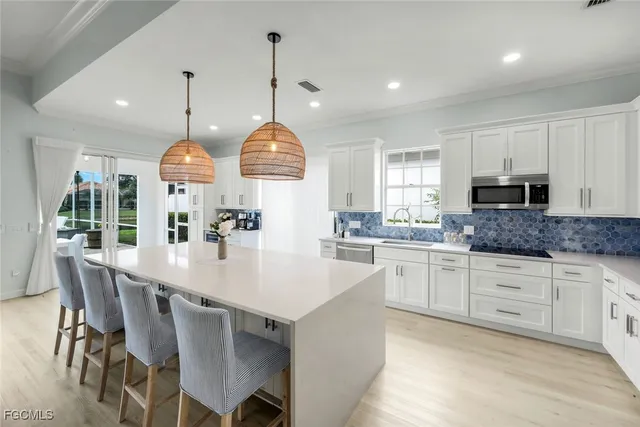 a kitchen with stainless steel appliances kitchen island granite countertop a stove a sink a dining table and chairs with wooden floor