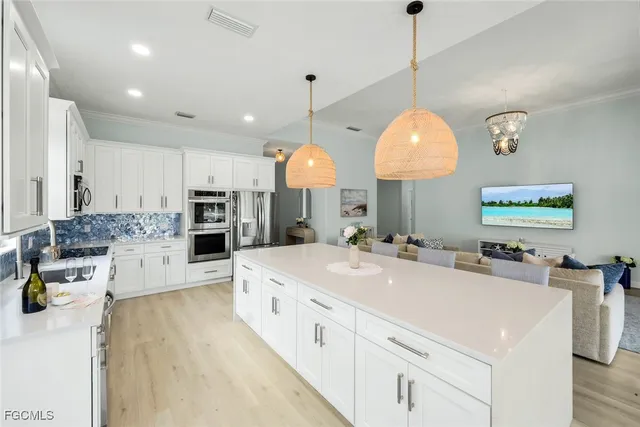 a large white kitchen with kitchen island a stove a sink a center island and cabinets