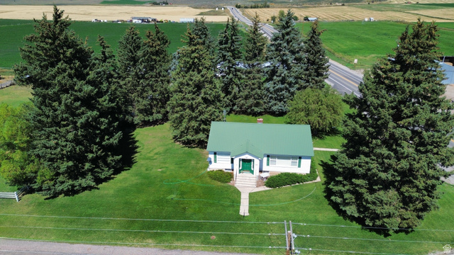 114 West 7th Street Georgetown, ID 83239 - Photo 68 of 71 White residential structure with a green metal roof, a prominent front entrance, and a light-colored walkway, surrounded by extensive green lawn and mature evergreen trees