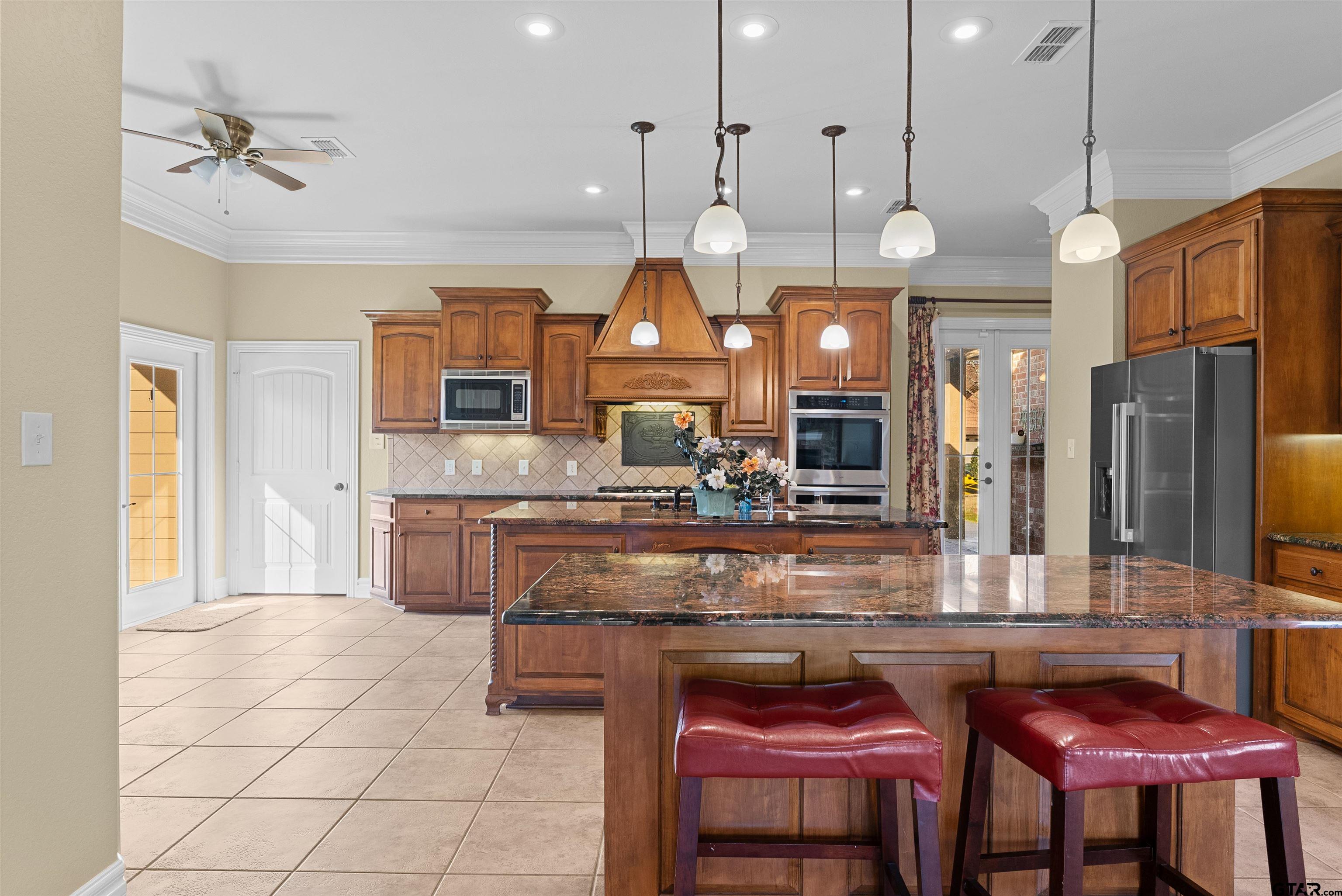 714 Huntwick Lane Tyler, TX 75703 - Photo 33 of 39 a kitchen with granite countertop a table chairs and a chandelier