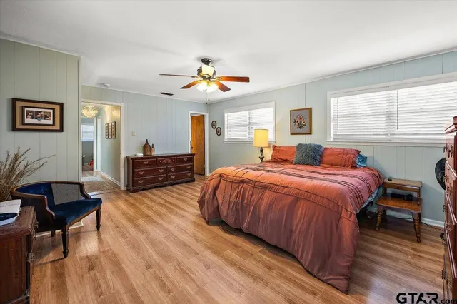 a spacious bedroom with a bed a dresser and wooden floor