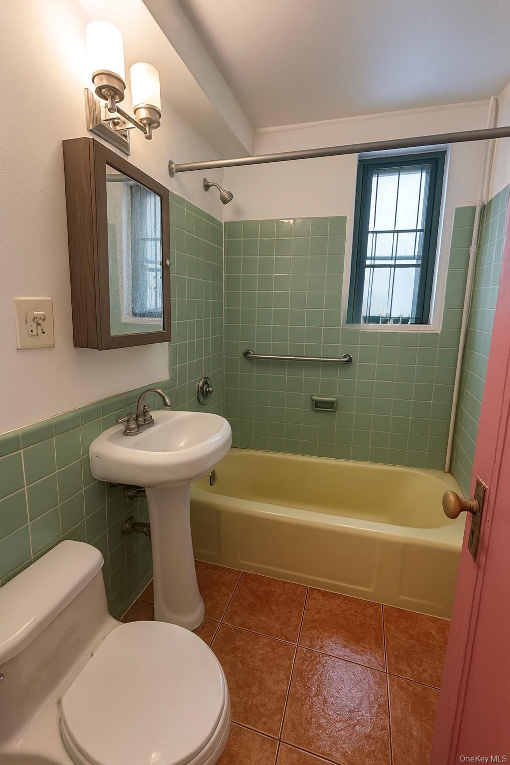 18 Metropolitan Ovl, Unit 3C Bronx, NY 10462 - Photo 2 of 6 Full bath with light tile patterned flooring, bathing tub / shower combination, tile walls, and wainscoting