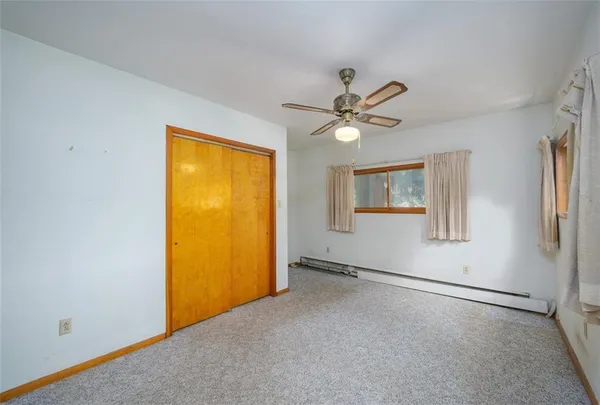 an empty room with a ceiling fan and window