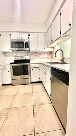 a kitchen with granite countertop a stove a sink and dishwasher