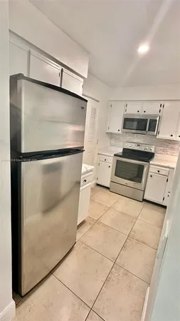 a kitchen with a refrigerator and a stove top oven