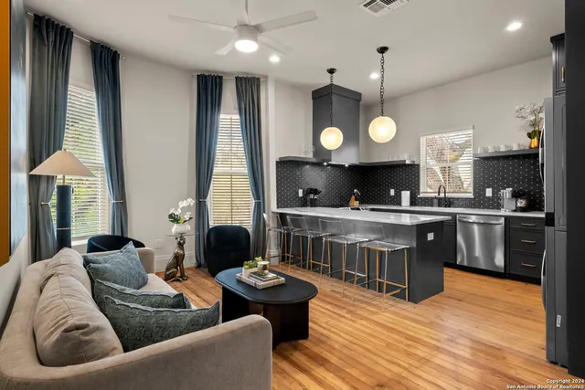 a living room with stainless steel appliances kitchen island granite countertop furniture and a wooden floor