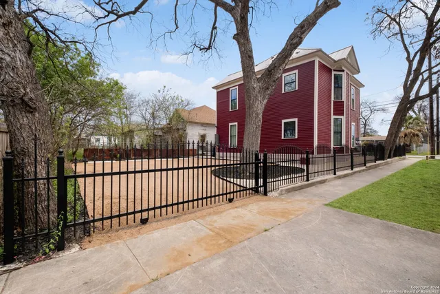 a view of a brick house with a small yard and a large tree