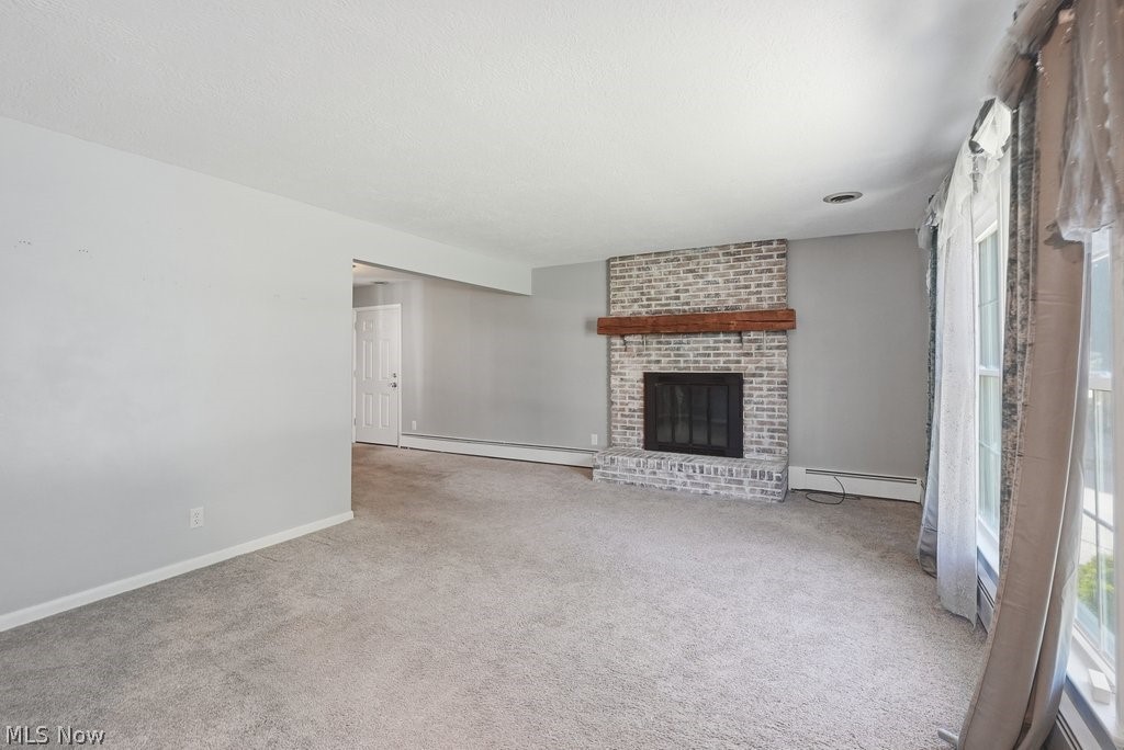 136 Pinehurst Road Munroe Falls, OH 44262 - Photo 5 of 48 Living area featuring a painted brick fireplace with a wood mantle, soft gray walls, and light gray carpeting