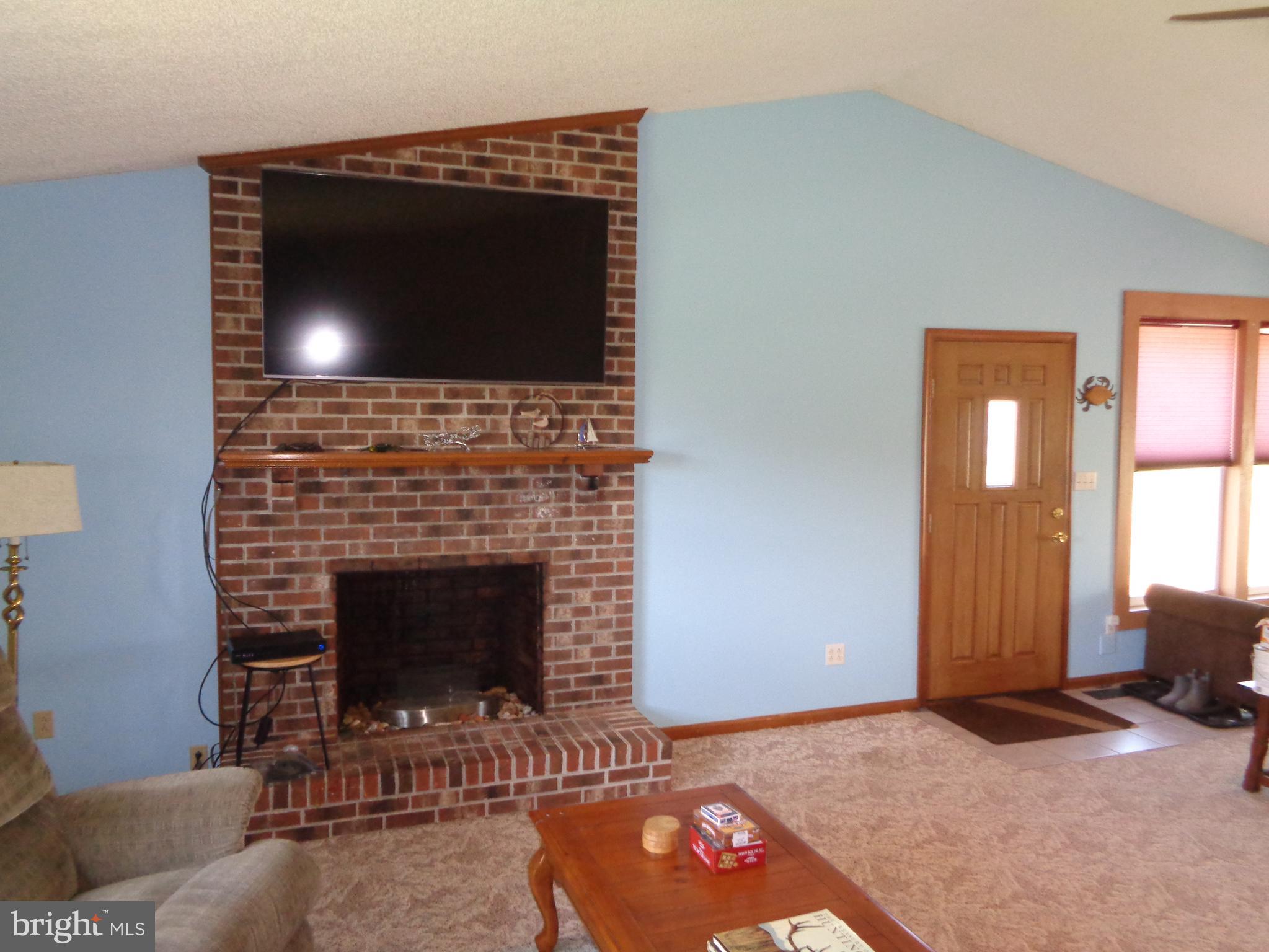 27174 Champ Wharf Road Princess Anne, MD 21853 - Photo 15 of 32 a living room with a fireplace and a flat screen tv