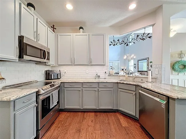 a kitchen with stainless steel appliances granite countertop wooden cabinets granite counter tops and a hard wood floors