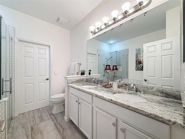 a bathroom with a granite countertop sink a toilet and a mirror