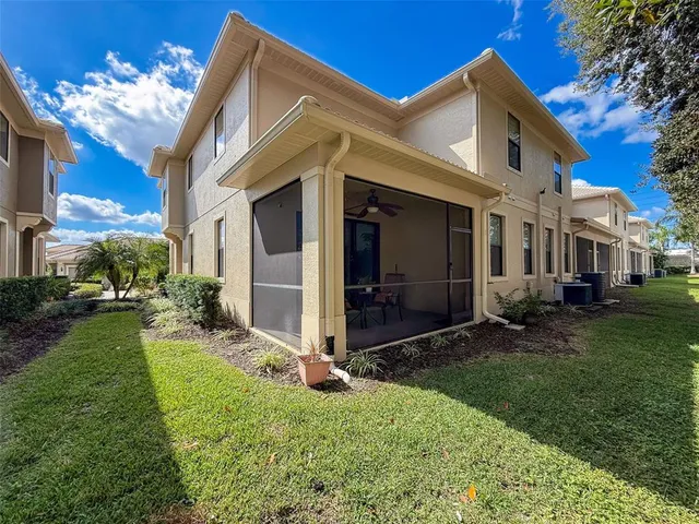 a view of a white house next to a yard with big trees
