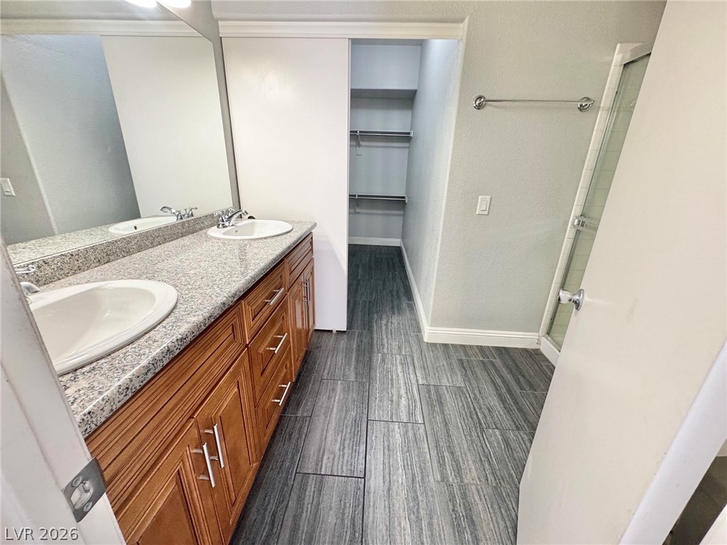 5304 Runningbrook Road Las Vegas, NV 89120 - Photo 10 of 22 A stone-countertop vanity and modern wood-look tile flooring elevate this bathroom space.