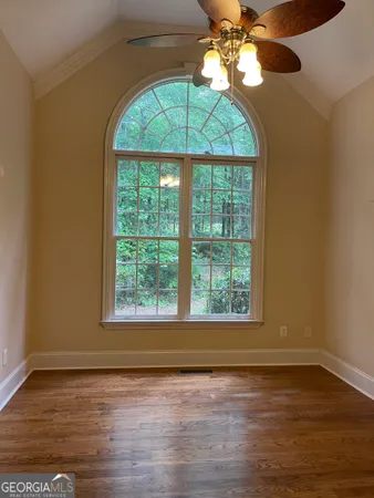 a view of an empty room with wooden floor and a window