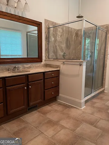 a bathroom with a granite countertop sink a mirror and a shower