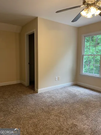 a view of an empty room with window and chandelier fan
