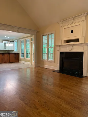 an empty room with wooden floor fireplace and windows