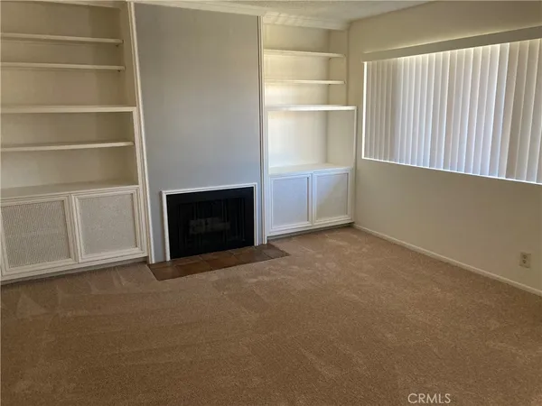 a view of an empty room with a fireplace and a window