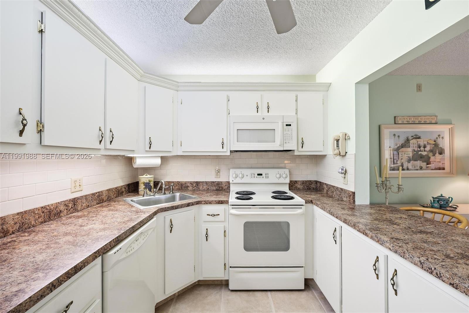 301 Pine Ridge Circle, Unit C1 Greenacres, FL 33463 - Photo 13 of 30 a kitchen with granite countertop white cabinets and white appliances