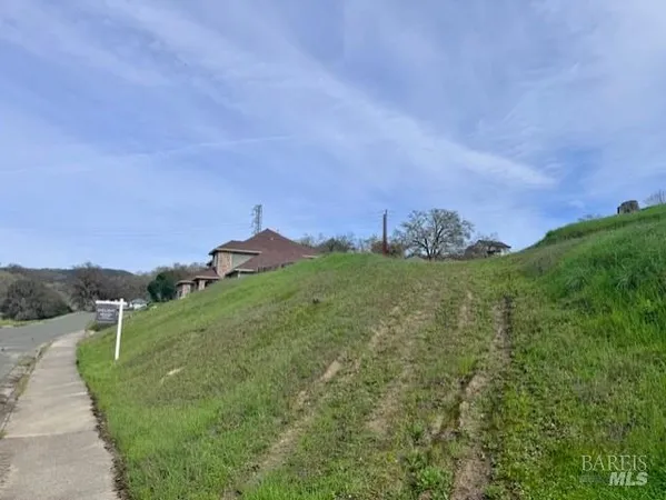 a view of a green field with sitting area in back