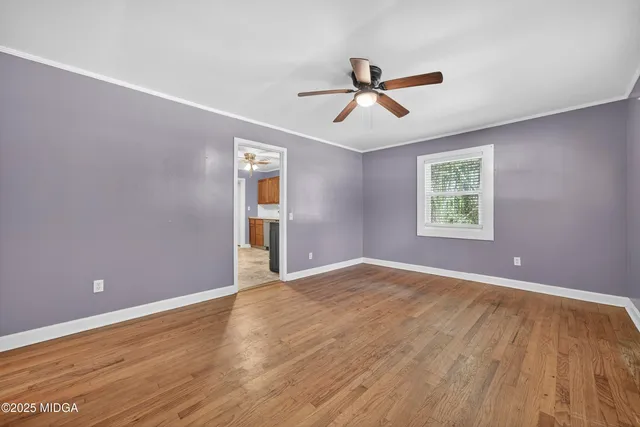 a view of an empty room with a window and wooden floor