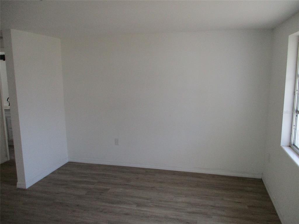 7925 Bracken Drive Port Richey, FL 34668 - Photo 2 of 11 a view of an empty room with wooden floor and a window