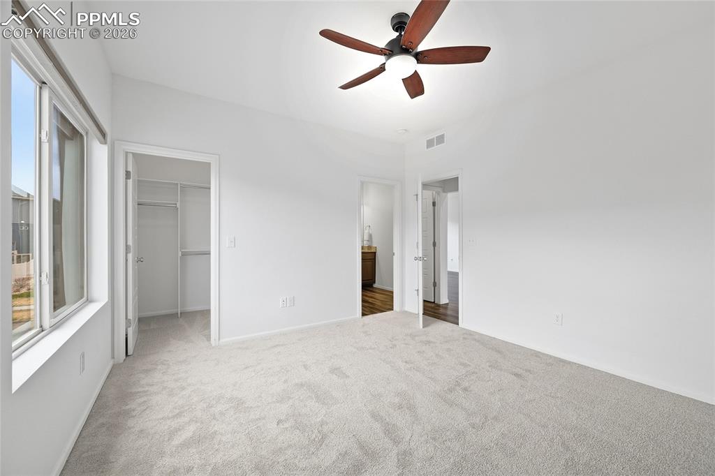 9414 Timberlake Loop Colorado Springs, CO 80927 - Photo 18 of 40 Unfurnished primary bedroom with light carpet floors, a walk in closet, a ceiling fan, and ensuite bath