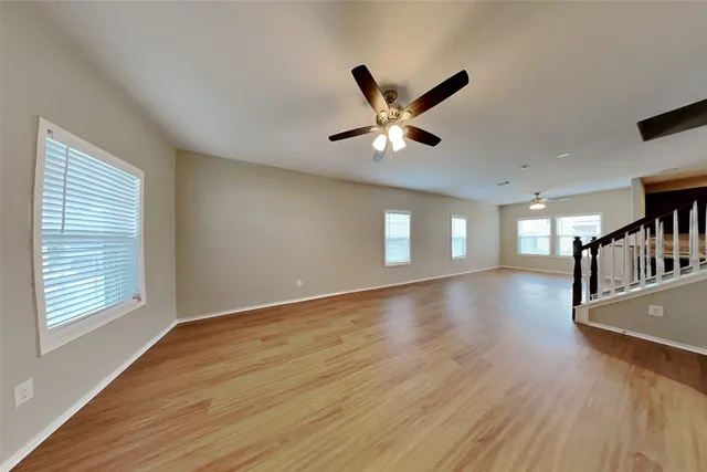 a view of an empty room with window and wooden floor