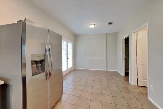 a view of a refrigerator in kitchen and an empty room