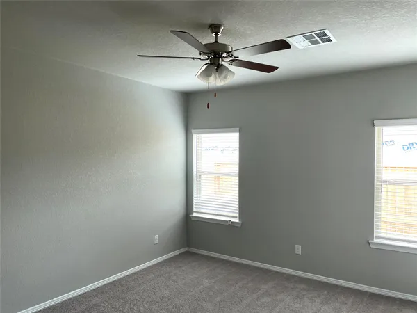 an empty room with windows and fan