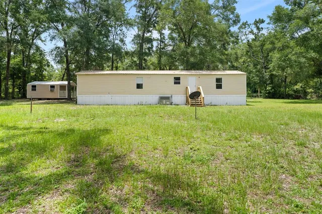 a backyard of a house with large trees and plants
