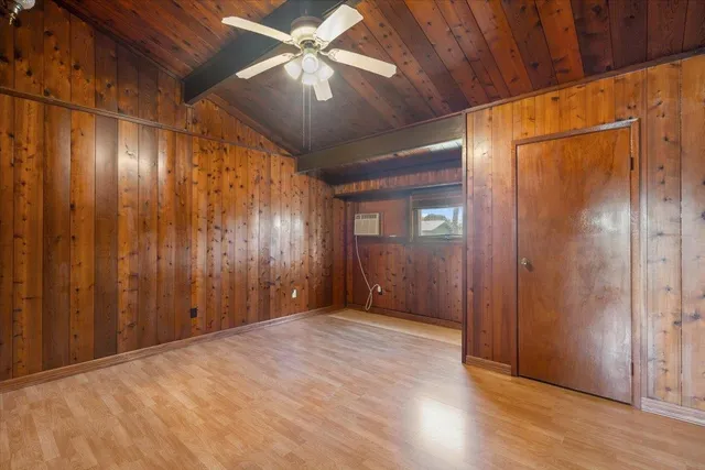 an empty room with wooden floor closet and windows