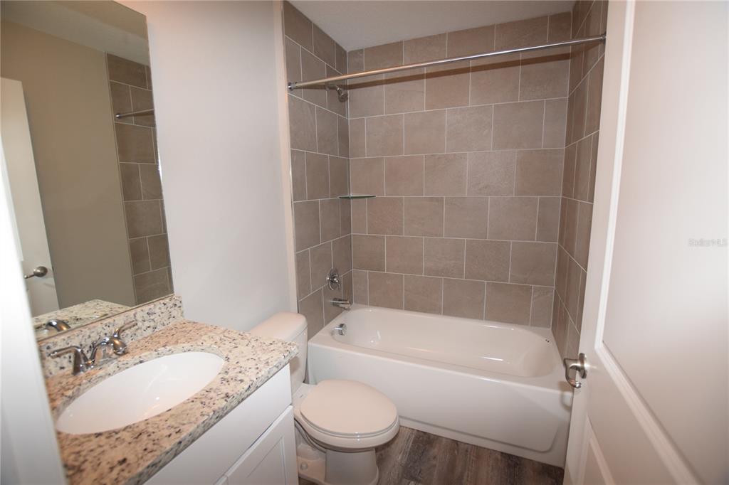 220 Danvers Street Eustis, FL 32726 - Photo 12 of 15 a bathroom with a granite countertop sink toilet mirror and bathtub