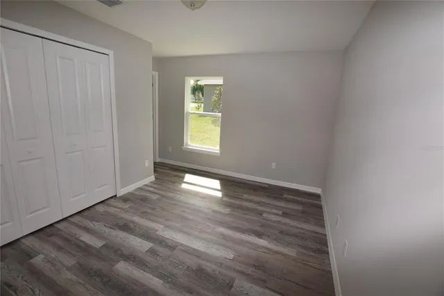 a view of an empty room with a window and wooden floor