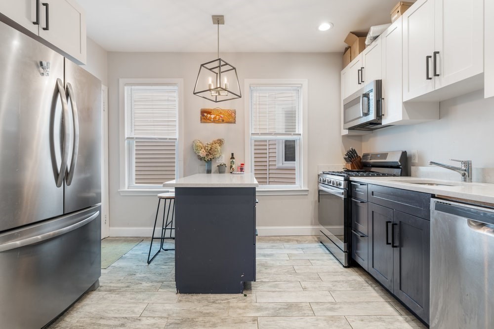 24 Buttonwood Street Boston, MA 02125 - Photo 20 of 42 a kitchen with stainless steel appliances granite countertop a refrigerator a sink dishwasher a stove and a dining table with wooden floor