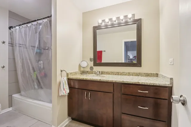 a bathroom with a granite countertop sink vanity mirror and bathtub