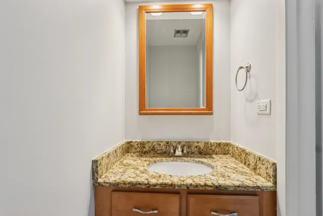 a bathroom with a granite countertop sink and a mirror