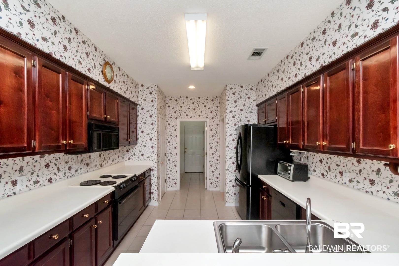 1032 Cross Gates Place Mobile, AL 36609 - Photo 12 of 34 Kitchen with black appliances, light tile patterned floors, light countertops, and reddish brown cabinets
