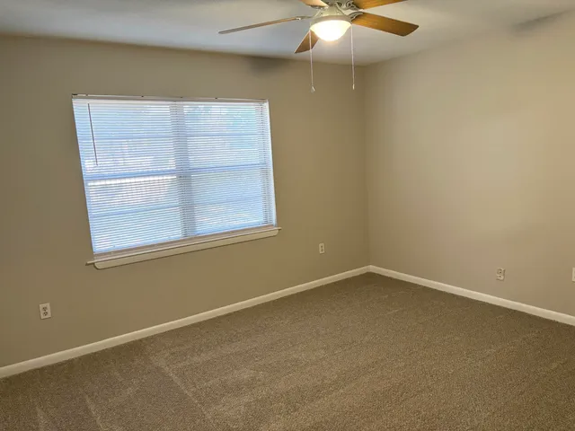 an empty room with a window and a fan