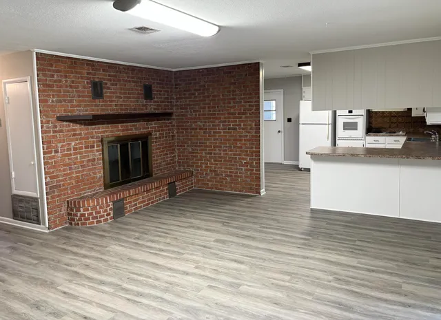 a view of a kitchen with wooden floor and a fireplace