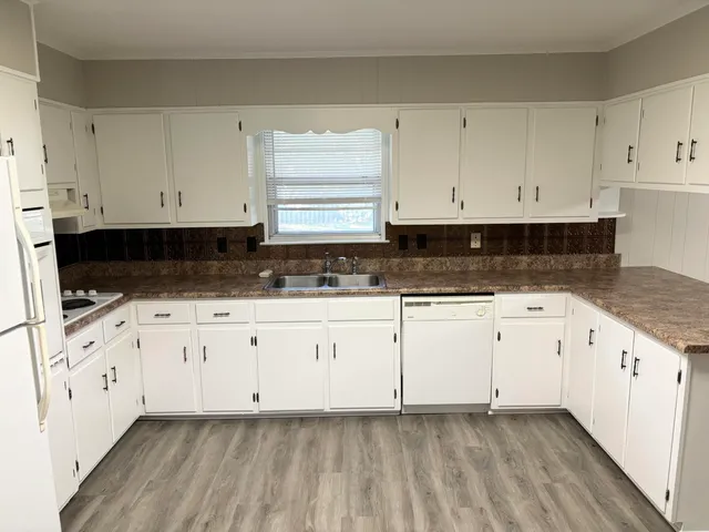 a kitchen with granite countertop white cabinets and sink