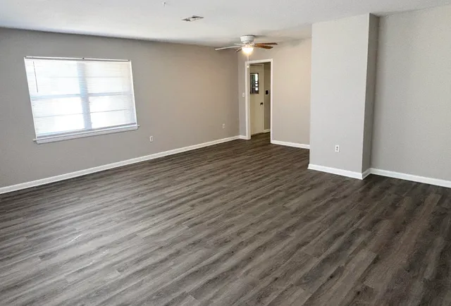 an empty room with wooden floor and windows