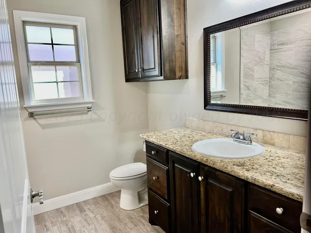 a bathroom with a granite countertop sink a toilet and a mirror
