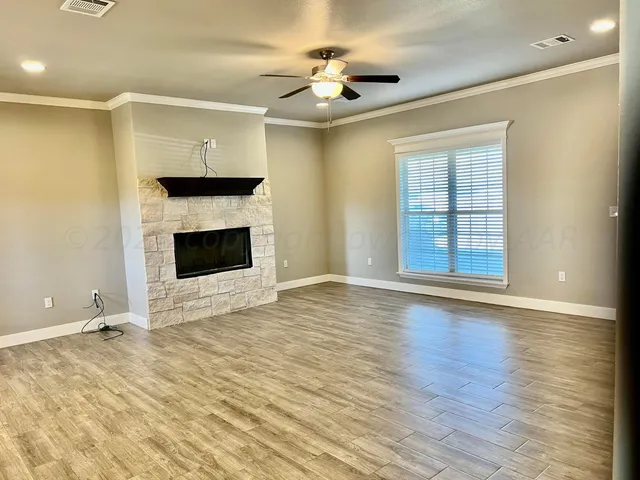 a view of an empty room with window and wooden floor