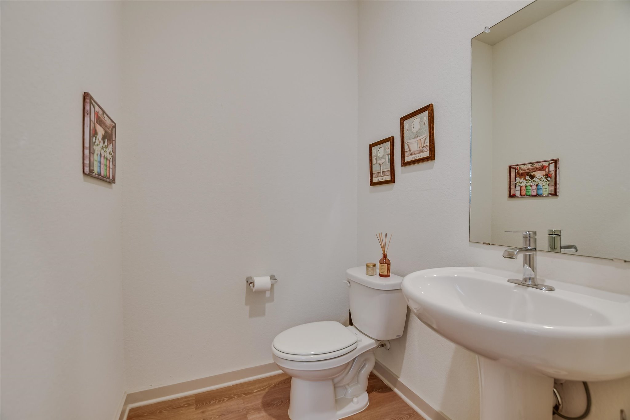 105 Merrick Road Georgetown, TX 78628 - Photo 17 of 23 A well-appointed powder room features a pedestal sink, modern toilet, and attractive wood-look flooring.